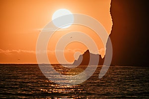 A red burning sunset over the sea with rocky volcanic cliff. Abstract nature summer or spring ocean sea background