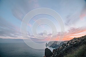 A red burning sunset over the sea with rocky volcanic cliff. Abstract nature summer or spring ocean sea background