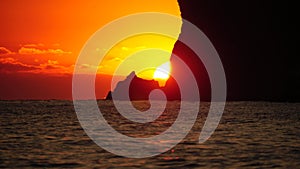 A red burning sunset over the sea with rocky volcanic cliff. Abstract nature summer or spring ocean sea background