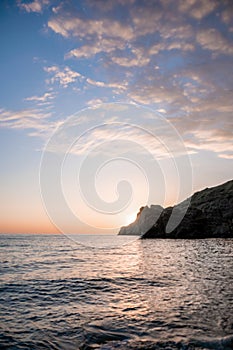 A red burning sunset over the sea with rocky volcanic cliff. Abstract nature summer or spring ocean sea background.