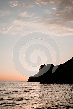 A red burning sunset over the sea with rocky volcanic cliff. Abstract nature summer or spring ocean sea background.