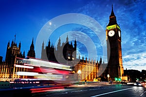 Red bus, Big Ben and Westminster Palace in London, the UK. at night. Moon shining