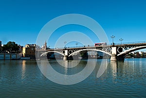 The red bus passes over the Triana bridge over the Guadalquivir river in Seville photo