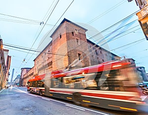 Red bus speeding up in Bologna streets at dusk