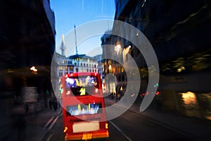 Red bus on street by night in London