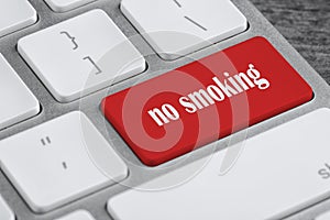 Red button with phrase No smoking on computer keyboard, closeup