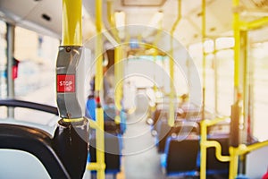 Red button STOP on the bus. Bus with yellow handrails and blue seats. Photo with the sun effect, glare on the lens from the light.