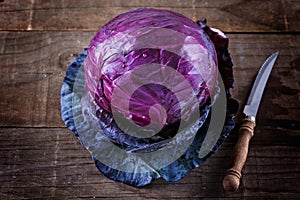 Red cabbage and knife over rustic wooden background