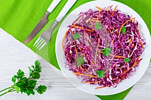 Red cabbage salad with carrots and parsley on white dish