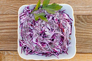 Red cabbage salad with onion and mayonnaise on wooden table. Top view