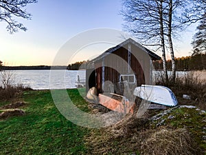 Red cabin with two boats near the lake in Sweden