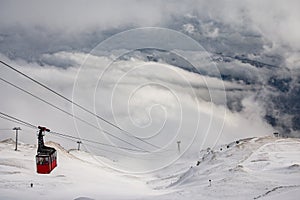 Red cable car descend from mountain peak