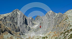 A red cable car on its way from Skalnate pleso to Lomnicky peak. Red gondola moving up to Lomnica peak in High Tatras Mountains.