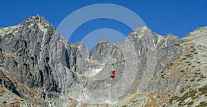 A red cable car on its way from Skalnate pleso to Lomnicky peak. Red gondola moving up to Lomnica peak in High Tatras Mountains.