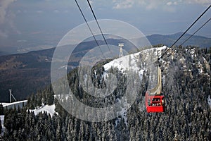 Red cable car over the forest covered with snow