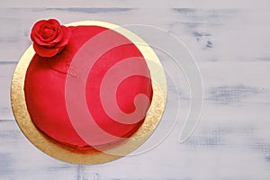 Red cake covered with marzepan or mastic and decorated with a flower, copy space