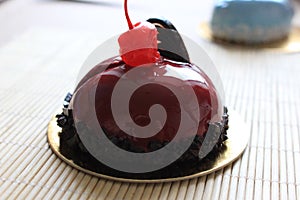 Red cake decorated with cherry and chocolate feather