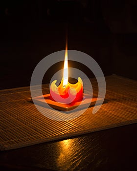 Red candle on bamboo mat with reflection 2