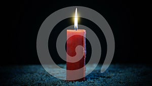 Red candle burning on dark background