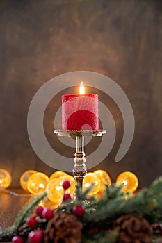 A red candle burns on a candelabra on a black background.