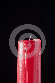 Red candle extinguished on black background