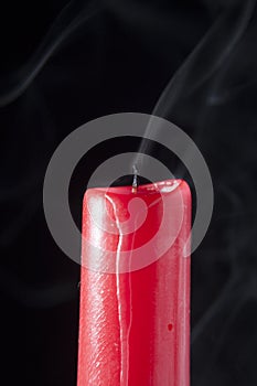 Red candle extinguished and with smoke on black background