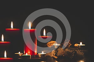 Red Candle with fire against defocused lights in darkness with golden bokeh in the dark Background