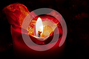 Red candle with flame and melting wax against a dark background