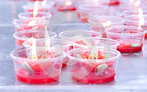 Red candle flames in plastic cup.