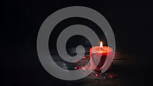 A red candle with a heart image burns on a dark background. Copy space.