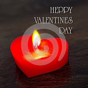 Red candle shaped heart on a dark background with the words happy Valentines day. Congratulations on Valentine`s Day_