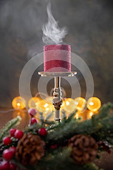 A red candle stands on a candelabra on a black background.