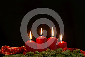 Red candles of an Advent wreath with fir branches
