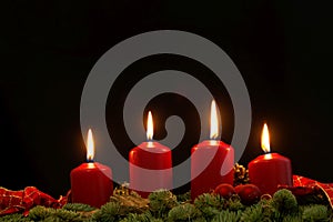 Red candles of an Advent wreath with fir branches