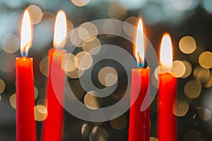 Red candles.Burning candles on bokeh background.Christmas festive background with red burning candles and bokeh garland