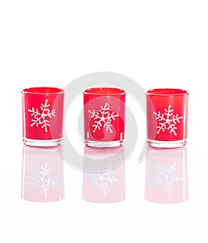 3 red candles, candle holders with crystal snowflakes isolated on reflective white perspex background photo