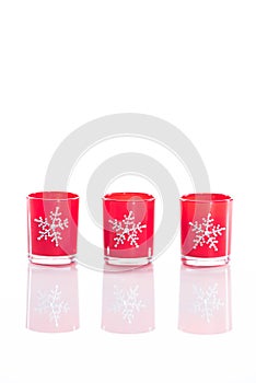 3 red candles, candle holders with crystal snowflakes isolated on reflective white perspex background with copy space photo