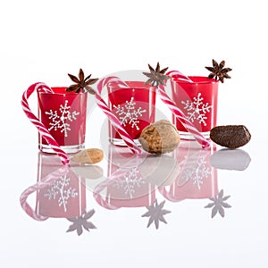 Red candles, candle holders with crystal snowflakes, sugar canes, anise stars and nuts, isolated on reflective white perspex photo