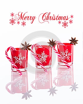 Red candles, candle holders with crystal snowflakes and sugar canes on reflective white perspex background with copy spac photo