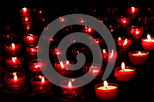 Red candles with glowing lights in darkness in church. Peace and hope background. Religion concept.