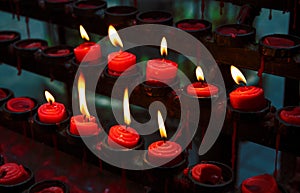 Red candles with yellow flame on catholic church altar. Burning candle closeup photo. In memoriam banner template