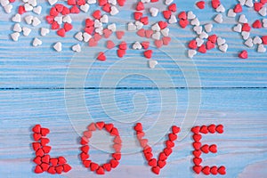 Red candy hearts laying on light blue painted rustic wooden background