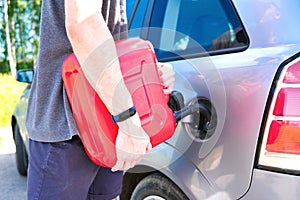 Red canister in the hands of a man. Filling a stalled car with gasoline from a canister