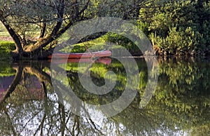 Red Canoe on Riverbank