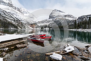 Red canoes parked in snowy valley at wooden pier. Lake O`hara, Yoho national park