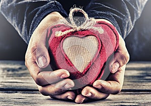 Red canvas valentine heart in the hands of a child. Heart gift as a token of love.