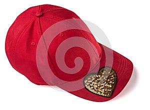 Red cap with golden sequin heart patch on white background