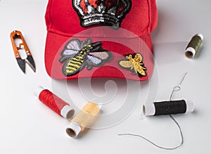 Red cap with various patches, threads, scissors and a neele on white background photo