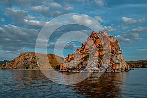 Red cape Shamanka rock in blue Lake Baikal, clouds, sunset, reflection, ripples
