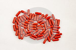 Red capsules pills heap on white background. Medicine pharmacy concept. Close up top view